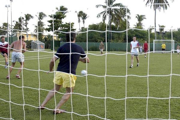 Gruppe von Männern spielt Fußball auf einem gepflegten Rasenfeld im Freien, Grand Palladium Bavaro Suites Resort & Spa
