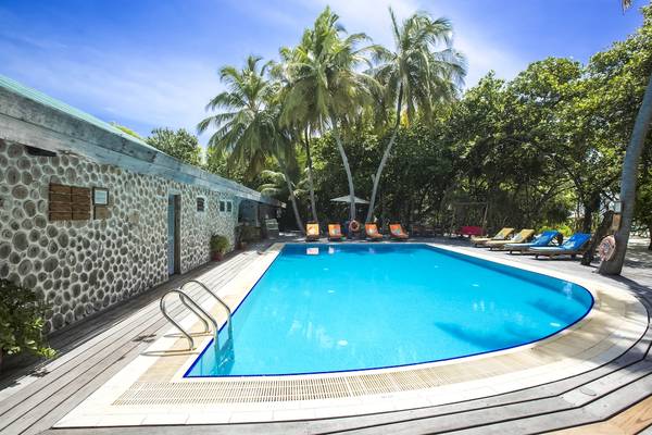 Außenpool am Reethi Beach Resort mit Liegestühlen und Palmen im Hintergrund