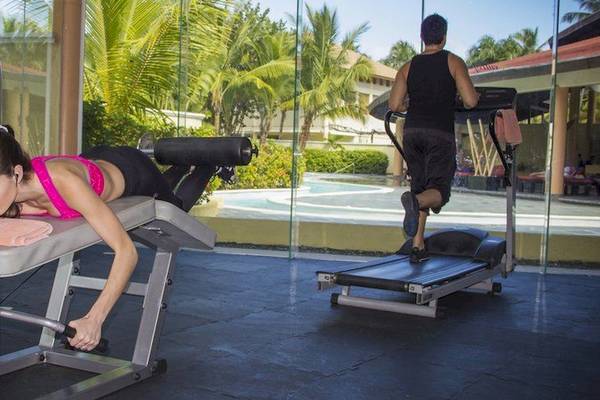 Fitnesscenter Workout Szene mit Frau auf Bankdrücken und Mann auf Laufband.