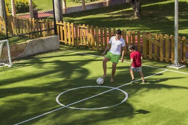 Mann und Kind spielen Fußball auf einem Fußballfeld im Grand Palladium Bavaro Suites Resort & Spa.