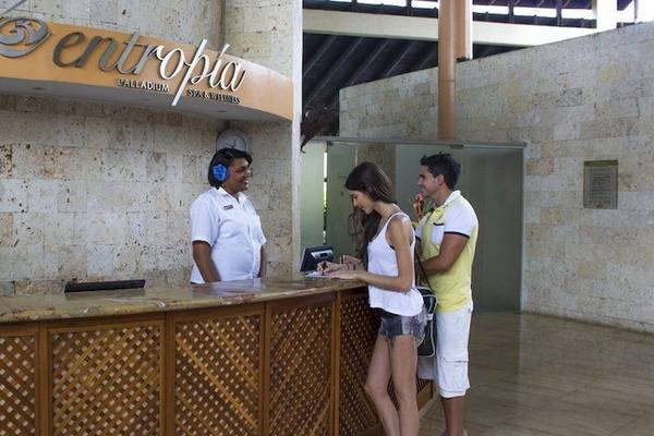 Empfangsbereich des Grand Palladium Bavaro Suites Resort & Spa mit einer Rezeptionistin und Gästen.