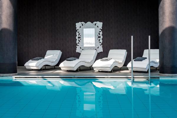 Fünf weiße Liegestühle neben einem Swimmingpool im Diamond Deluxe Hotel.