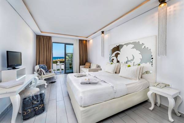 Innenansicht eines Zimmers im Diamond Deluxe Hotel mit einem großen Bett, Fernseher, Schreibtisch und Balkon.