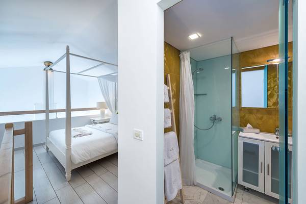 Schlafzimmer und Badezimmer im Diamond Deluxe Hotel mit vierposterbett und blauer Duschkabine.