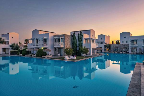 Sonnenuntergang über dem Swimmingpool des Diamond Deluxe Hotels mit weißen Gebäuden und Loungeliegen