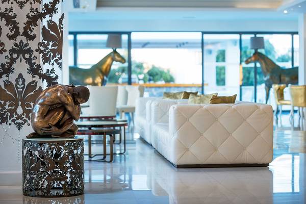 Innenansicht des Diamond Deluxe Hotels mit einer Bronzestatue, weißen Sofas und goldenen Pferdestatuen im Hintergrund.