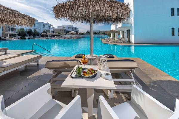 Loungebereich am Pool des Diamond Deluxe Hotels mit Sonnenschirmen, Liegestühlen und Essenstablett.