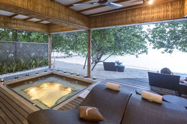 Außenbereich des Reethi Beach Resorts mit Jacuzzi und Blick auf den Strand.