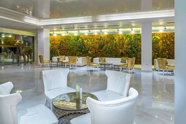 Lobby des Diamond Deluxe Hotels mit weißen Sofas und Tischen vor einer grünen Wand
