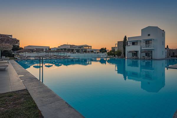 Sonnenuntergang am Infinity-Pool des Diamond Deluxe Hotels mit luxuriösen Liegestühlen und weißen Gebäuden im Hintergrund.