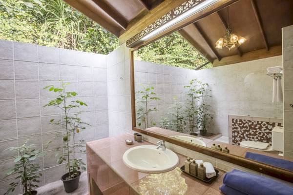 Badezimmer im Reethi Beach Resort mit Pflanzen, Waschbecken und Spiegel.