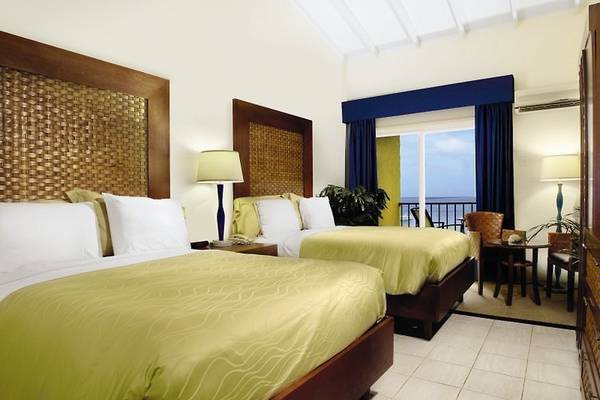 Zwei Doppelbetten in einem Hotelzimmer des Divi Flamingo Beach Resort and Casino mit Blick auf das Meer.
