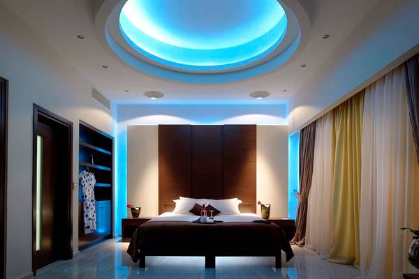 Schlafzimmer im Royal Blue Resort mit runden Deckenleuchten, einem großen Bett und Nachttischen.