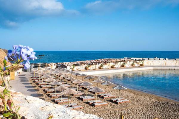 Strand des Royal Blue Resorts mit vielen Sonnenliegen und Sonnenschirmen.