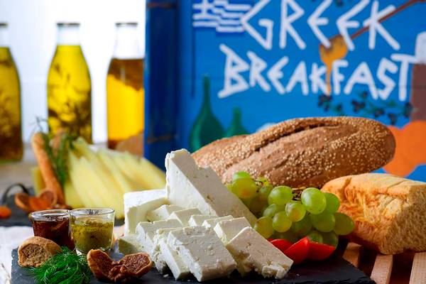 Griechisches Frühstücksbuffet mit Brot, Käse und Obst auf einem schwarzen Brett.