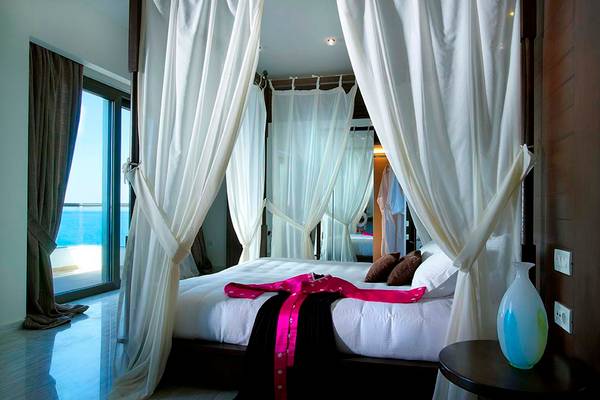 Bett im Royal Blue Resort mit Meerblick, weiße Vorhänge und moderne Einrichtung.