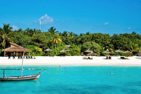 Strand des Reethi Beach Resorts mit Boot im Wasser und Sonnenschirmen
