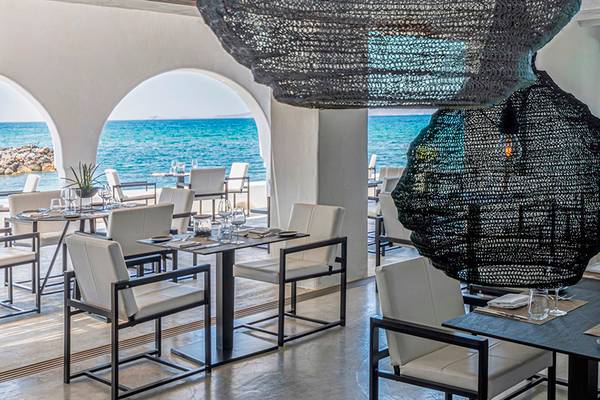 Innenansicht des Restaurants im Knossos Beach Bungalows Suites Resort & Spa mit Blick auf das Meer.