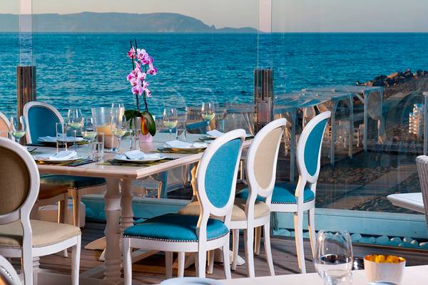 Außenbereich des Restaurants des Knossos Beach Bungalows Suites Resort & Spa mit Blick auf das Meer.