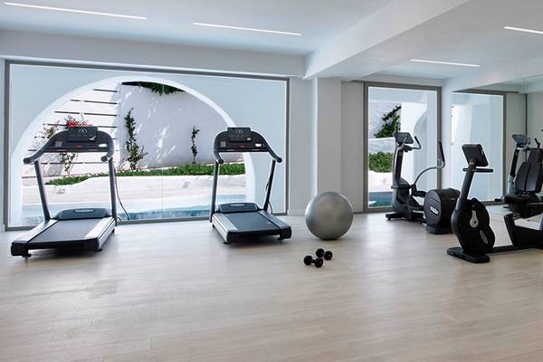 Fitnesscenter im Knossos Beach Bungalows Suites Resort & Spa mit Laufbändern, Trainingsgeräten und einem großen Fenster