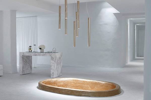 Innenansicht des Knossos Beach Bungalows Suites Resort & Spa mit ovaler Badewanne, Tisch und Lampen.