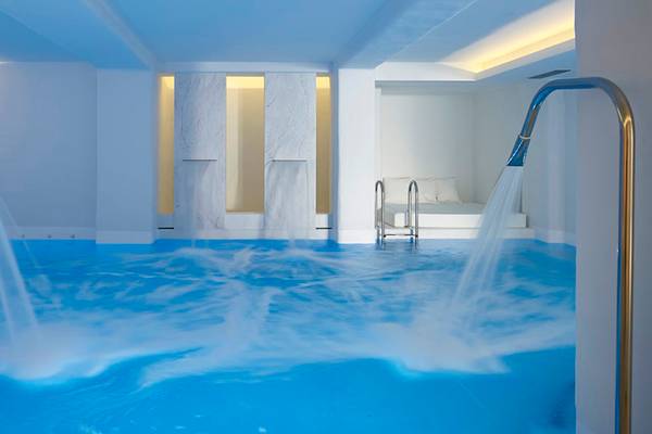 Innenpool im Knossos Beach Bungalows Suites Resort & Spa mit Wasserstrahlen und weißen Wänden