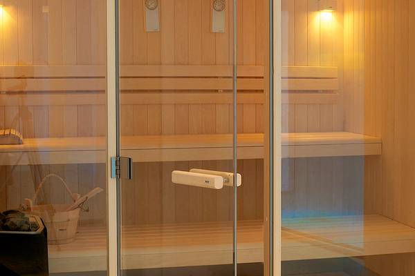 Innenansicht der Sauna im Knossos Beach Bungalows Suites Resort & Spa mit Holzbänken und offenem Türgriff.