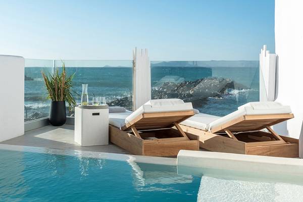 Balkonbereich des Knossos Beach Bungalows Suites Resort & Spa mit Blick auf das Meer und zwei Liegen.
