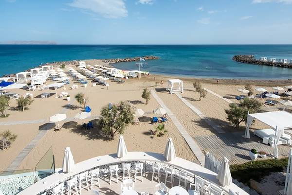 Luftaufnahme des Knossos Beach Bungalows Suites Resort & Spa mit vielen Sonnenliegen und Sonnenschirmen am Strand