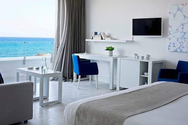 Innenansicht eines Zimmers im Knossos Beach Bungalows Suites Resort & Spa mit Blick auf das Meer.