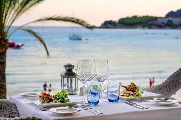 Tisch am Strand im Secrets Mallorca Villamil Resort & Spa mit Blick auf das Meer und eine Palme