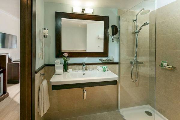 Badezimmer mit Dusche, Spiegel und Waschbecken im Secrets Mallorca Villamil Resort & Spa