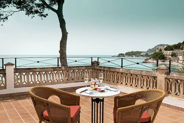 Balkon mit Meerblick im Secrets Mallorca Villamil Resort & Spa mit Tisch, zwei Stühlen und Aussicht auf das Meer.