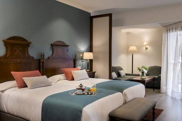 Doppelbett-Zimmer im Secrets Mallorca Villamil Resort & Spa mit blauen Decken und Dekor.