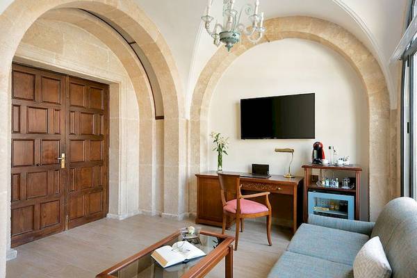 Innenansicht eines Zimmers im Secrets Mallorca Villamil Resort & Spa mit Schreibtisch, Stuhl und Fernseher.