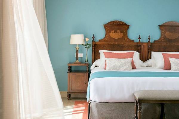 Doppelbett im Schlafzimmer mit blauer Wand, Dekor, Lampen und Kissen.