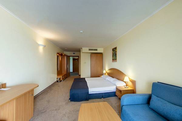 Doppelzimmer im Bellevue Hotel mit zwei Betten, Schreibtisch, Couch und Nachttischen.