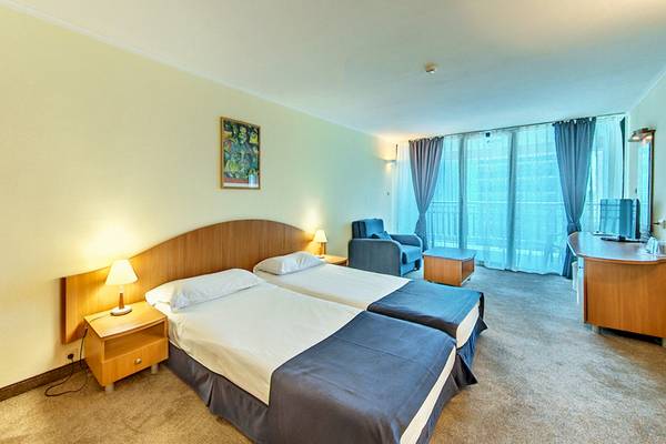Doppelzimmer im Bellevue Hotel mit zwei Betten, Nachttischen, Lampen, einem Schreibtisch und einer Sitzecke.