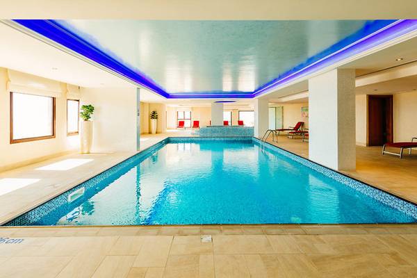 Innenpool des Marjan Island Resort & Spa mit blauen Beleuchtung und Lounge-Bereich.