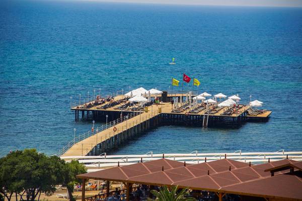 Aussicht auf die Pier des Arcanus Side Resort am Meer mit Sonnenschirmen und Liegen.