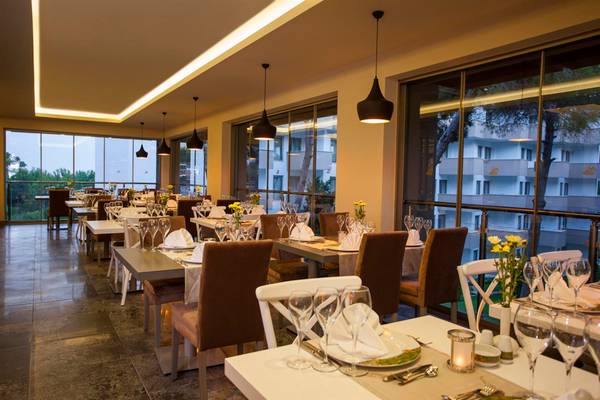 Innenansicht des Restaurants im Arcanus Side Resort mit gedeckten Tischen und großen Fenstern.