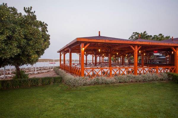 Außenbereich des Arcanus Side Resort mit Pavillon, Rasen und Bäumen.