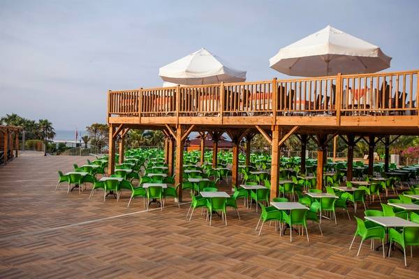 Terrasse im Arcanus Side Resort mit grünen Stühlen und Tischen unter Sonnenschirmen