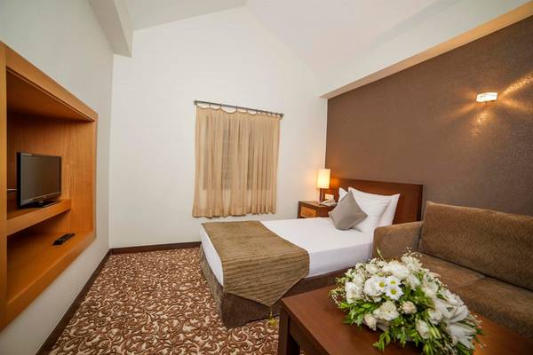 Arcanus Side Resort Hotelzimmer mit Bett, Fernseher und Sofa.