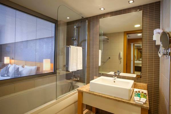 Badezimmer im Arcanus Side Resort mit Badewanne, Spiegel und Waschbecken.