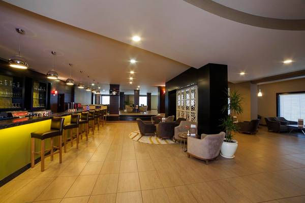Innenansicht der Bar im Arcanus Side Resort Hotel mit Holzboden, Barhockern und Loungemöbeln.