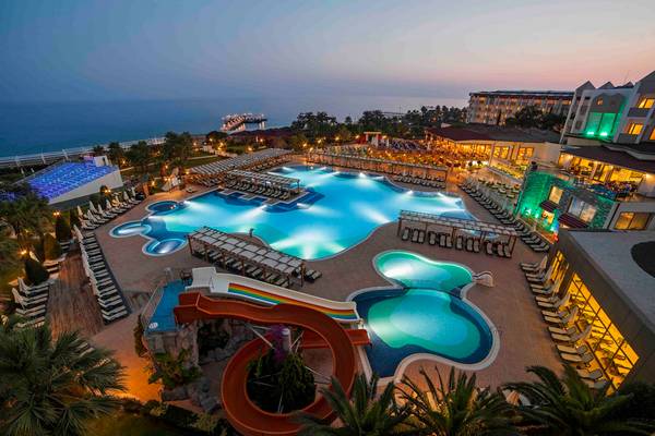 Luftaufnahme des Arcanus Side Resort mit Swimmingpools und Wasserrutschen bei Nacht.