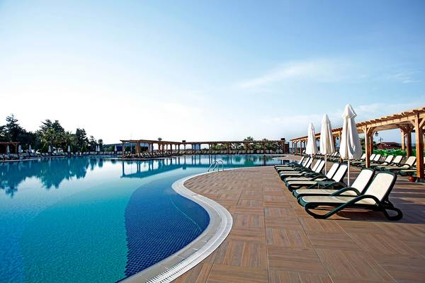 Schwimmbad-Loungebereich im Arcanus Side Resort mit Sonnenliegen und Sonnenschirmen.