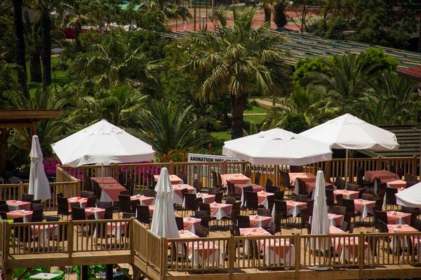 Terrasse des Arcanus Side Resort Hotels mit vielen Tischen und Sonnenschirmen.