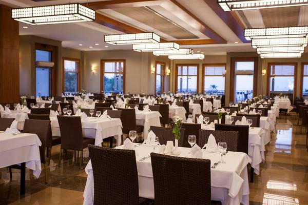 Innenansicht des Restaurants im Arcanus Side Resort Hotel mit gedeckten Tischen und modernen Deckenleuchten.